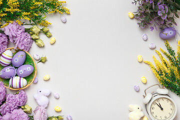 Easter composition. Violet and yellow flowers eggs in a basket alarm clock.