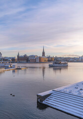 Obraz premium Arriving commuting boat at the Town City Hall pier a pale snowy winter day in Stockholm