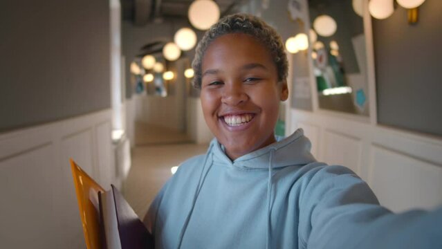 Young African-American woman student with books speaking on video call. Realtime