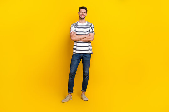 Full length photo of cheerful charming guy dressed striped t-shirt arms crossed isolated yellow color background