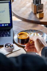 Cup of espresso coffee in hands of businessman working. Cafe environment restaurant table.