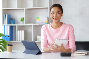 Woman in home office using tablet and mobile phone writing work schedule on notepad, Working from home.