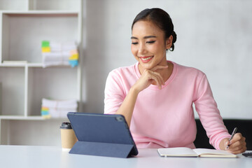 Woman in home office using tablet and mobile phone writing work schedule on notepad, Working from home.