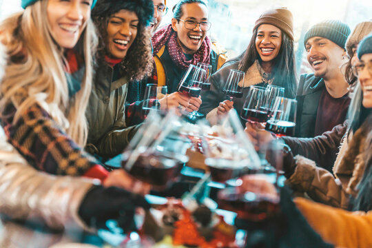 Happy Multiracial Friends Toasting Red Wine At Restaurant Balcony - Group Of Young People Wearing Winter Clothes Having Fun At Winebar Table - Dining Life Style And Friendship Concept