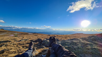 Hiker couple legs resting on alpine meadow with panoramic view on mountains seen from Ladinger...