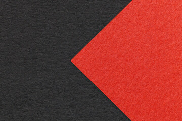 Fototapeta premium Texture of black paper background, half two colors with red arrow, macro. Structure of dense craft cardboard.
