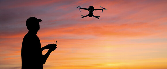 Silhouette of a man controls a drone on a sunset background	