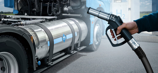Hand with H2 nozzle on a background of hydrogen fuel cell semi truck with H2 gas cylinder onboard....
