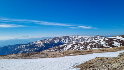 Scenic view on snow covered alpine hills and Karawanks mountains seen from alpine meadow at...