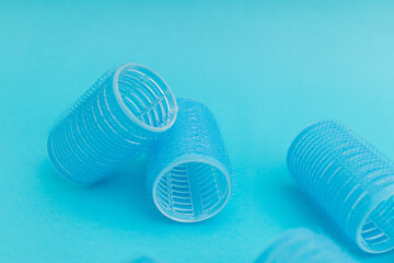 Large hair curlers on blue background, monochrome