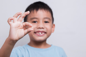 boy face looking at tooth and showing teeth behind on white background.
