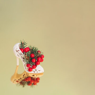 Retro high heel shoes full of Christmas decorations and tree branch on pastel pink background. Minimal winter holidays composition. Christmas and New Year concept.