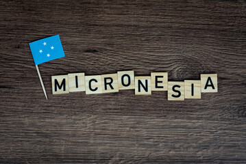 Fototapeta na wymiar Micronesia - wooden word with micronesia flag (wooden letters, wooden sign)