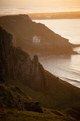 A building  tucked away on the cliffs during sunset, rhossilii, Gower, Wales.