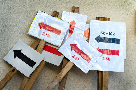 Arrow distance sign placards for giving direction in a heap against a wall, stock photo image