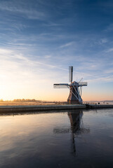 Dutch windmill at a frozen lake on a cold morning in december.