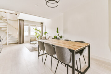 a dining room with white walls and hardwood flooring, including a wooden table surrounded by grey...