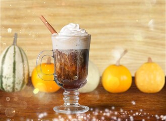 Tasty sweet iced latte with cream in glass with pumpkin.