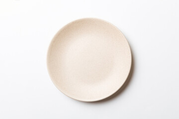 Top view of isolated of colored background empty round beige plate for food. Empty dish with space...