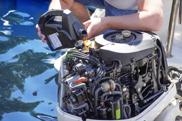   Man pouring and refueling engine motor oil into the engine for boat or yacht. - obrazy, fototapety, plakaty