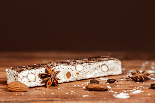 White chocolate dessert bar with almonds, nuts, coffee and cinnamon on wooden desk and brown bokeh background	- christmas sweets
