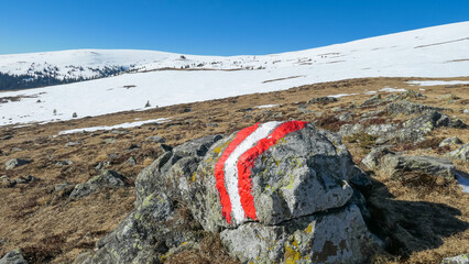 Directional path mark with Austrian flag painted on rock on the way to Ladinger Spitz, Saualpe,...