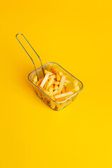 .close-up of french fries in a basket on a yellow background with free space for text