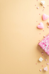 Valentine's Day concept. Top view vertical photo of giftbox heart shaped candles marshmallow and sprinkles on isolated beige background with empty space