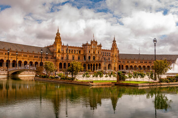Fototapeta premium Panorama of the Spain Square Plaza de Espana in Seville, with bridges over the canal, lake, fountain, towers and main entrance to the building. Example of Moorish and Renaissance revival.