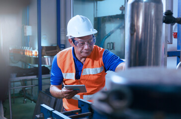 Professional asian male engineer in helmet using tablet to work, inspect and maintain electrical cabinet, machine