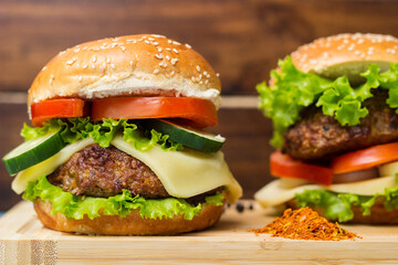 Burgers with beef meat, cheese and lettuce, served on cutting board