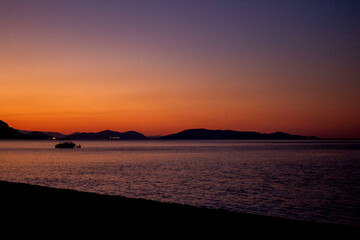 Sunset over calm ocean aerial panoramic view. Dramatic sunset seascape in Aegean Sea. Orange and blue color shades cloudy sky. Chalkidiki, Greece