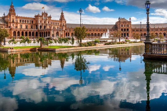Amazing Plaza de Espana in Seville, Spain. Water reflection of the palace buildings on the adjacent canal. One of major Spanish tourist attractions. Regionalism architecture.