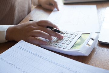Cropped image of professional businesswoman, entrepreneur or accountant working on a financial report paperwork at her desk, using calculator or laptop.