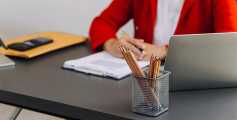Businessman hands working with finances about cost and calculator and laptop with tablet, smartphone at office in morning light