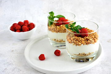 healthy dessert with yogurt and granola with raspberry decorated with mint leaves and berry