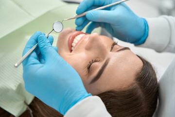 Dentist preparing to examine oral cavity of female client