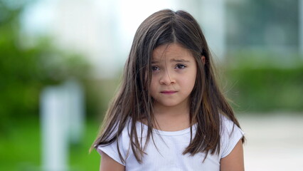 Portrait little girl with concerned emotion nervous child looking at camera