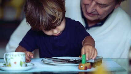 Candid grandson and grandfather bonding moment child plays with with car toy on grandparent lap