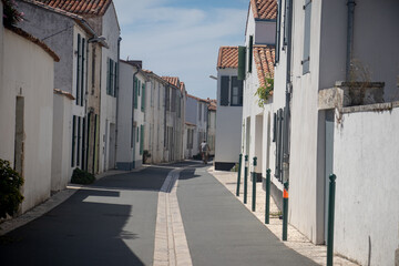 Sunny summer street in Ars en Ré on the Ile de Ré with white, pure and colourful buildings 