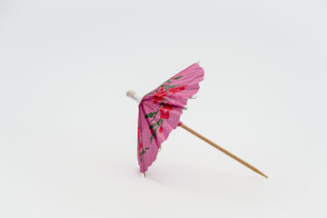 Single pink cocktail parasol umbrella isolated on a white background side view