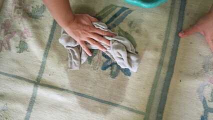 Cleaning rug removing stain closeup hand rubbing rug with cloth