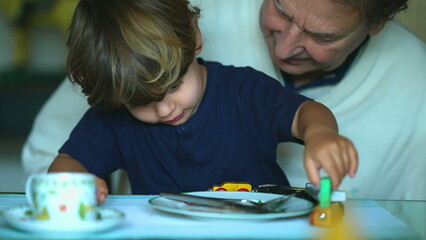 Child plays with wooden train toy on grandfather lap candid generation bonding moment