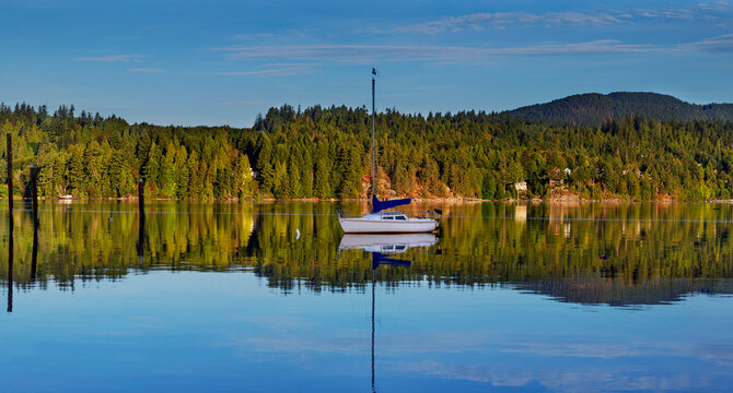 Sailboat moored in tranquil water along a shoreline
