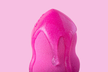 Closeup photography of beauty blender with dripping cosmetic gel on it.Neutral pink background.