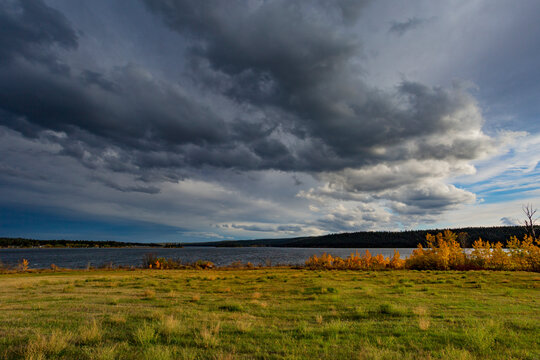 Clouds in a big sky over a lake and vast landscape, travelling on Highway 97 from Hush Lake to 108 Mile House; British Columbia, Canada