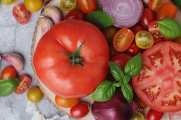 Flat lay composition of different tomatoes, onion, basil and garlic