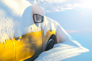 Yellow car buried under snow after blizzard and snowfall in residential area.Snowdrifts and freezed...