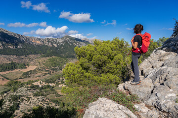 hiker woman with red backpack looking at the mountains and the valley, Orient valley , Bunyola,...