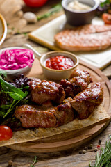 Kebab of pork with red onion and tomato sauce on wooden table macro close up vertical